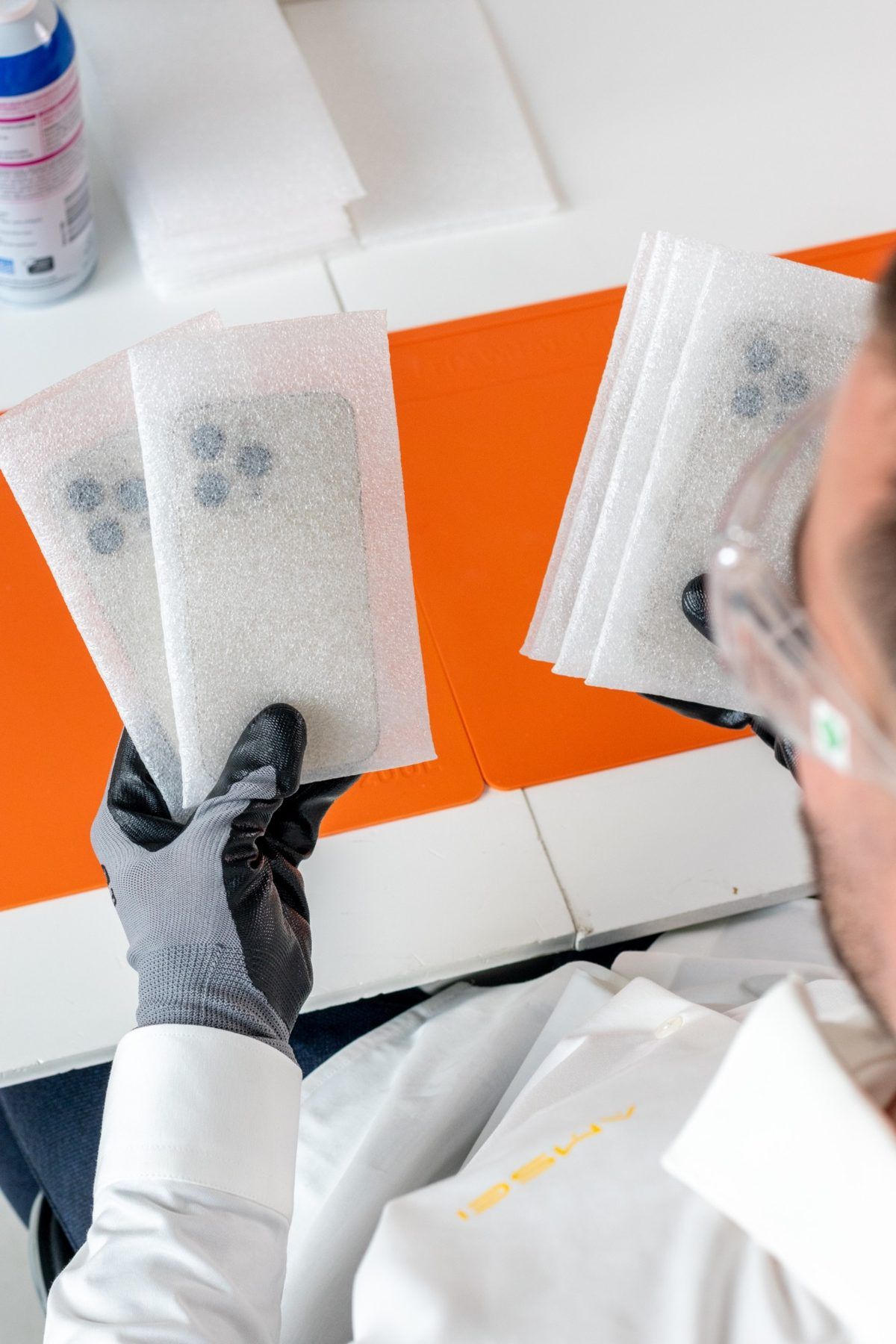 Técnico de AMSEI con guantes revisando iPhone protegidos en fundas de espuma
